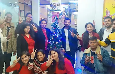 Students and staff celebrating Christmas around a decorated tree at Oxford School of Accounting