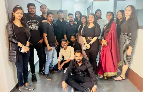 Students dressed in black and traditional attire posing after a celebration
