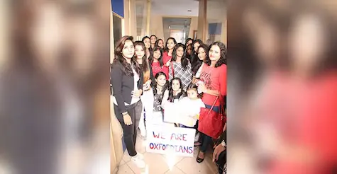 Girl students posing with Oxfordian placard